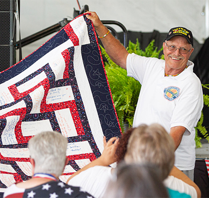 A man displaying a quilt