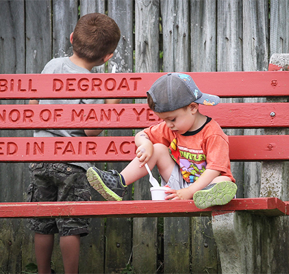 A boy on a bench eating ice cream